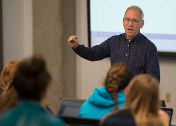 A professor teaches a lecture hall filled with students